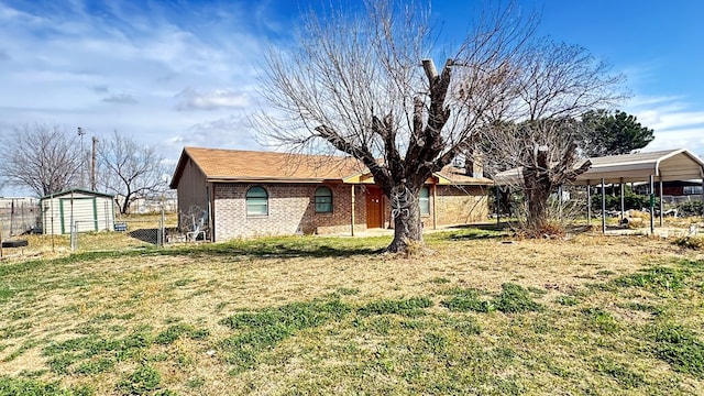 view of side of property with brick siding, a yard, a carport, and fence