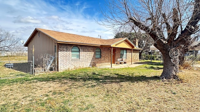 exterior space featuring fence, a patio area, brick siding, and a lawn