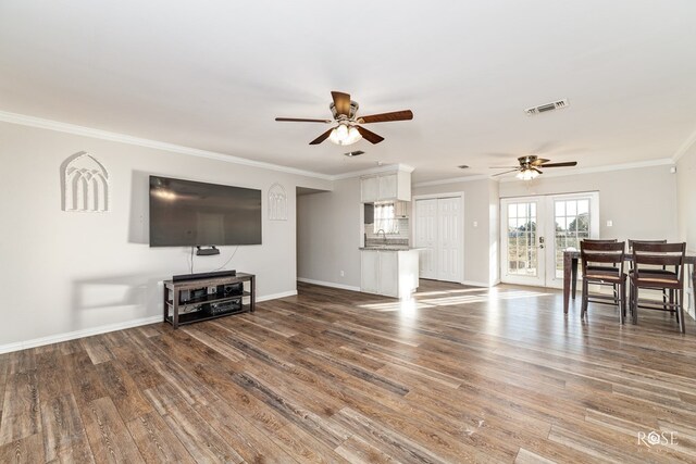 unfurnished living room featuring dark wood-type flooring, ornamental molding, and ceiling fan