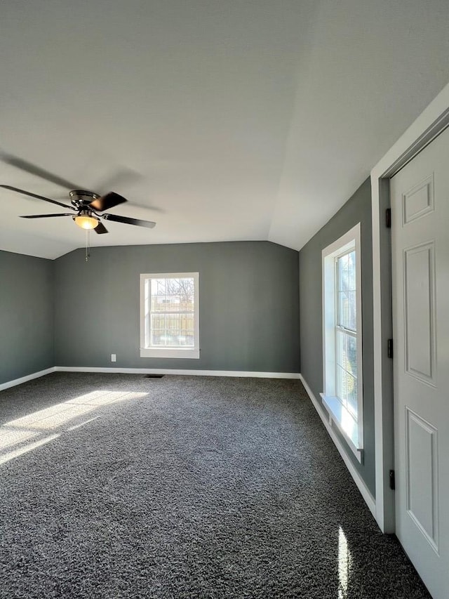 carpeted spare room with ceiling fan, baseboards, and lofted ceiling