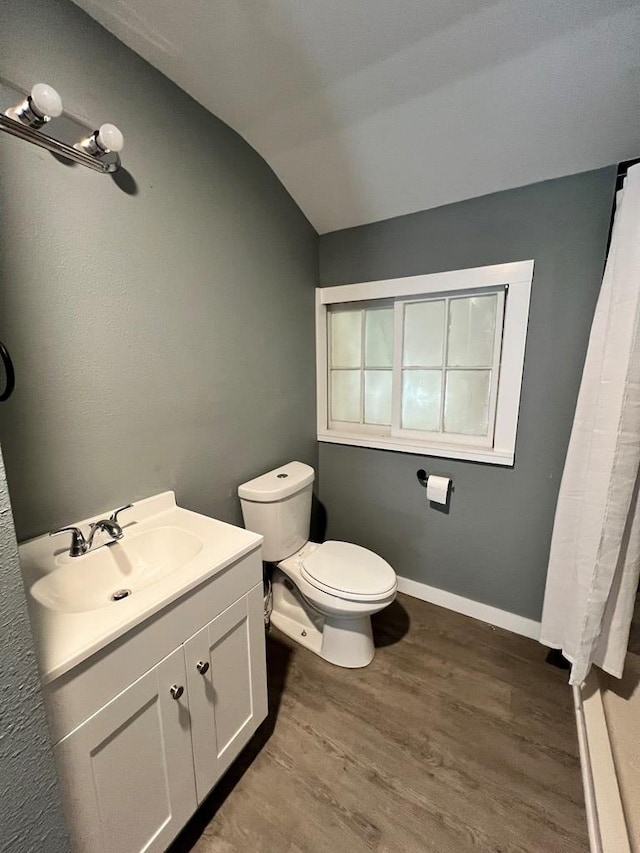 full bath featuring vanity, wood finished floors, baseboards, vaulted ceiling, and toilet