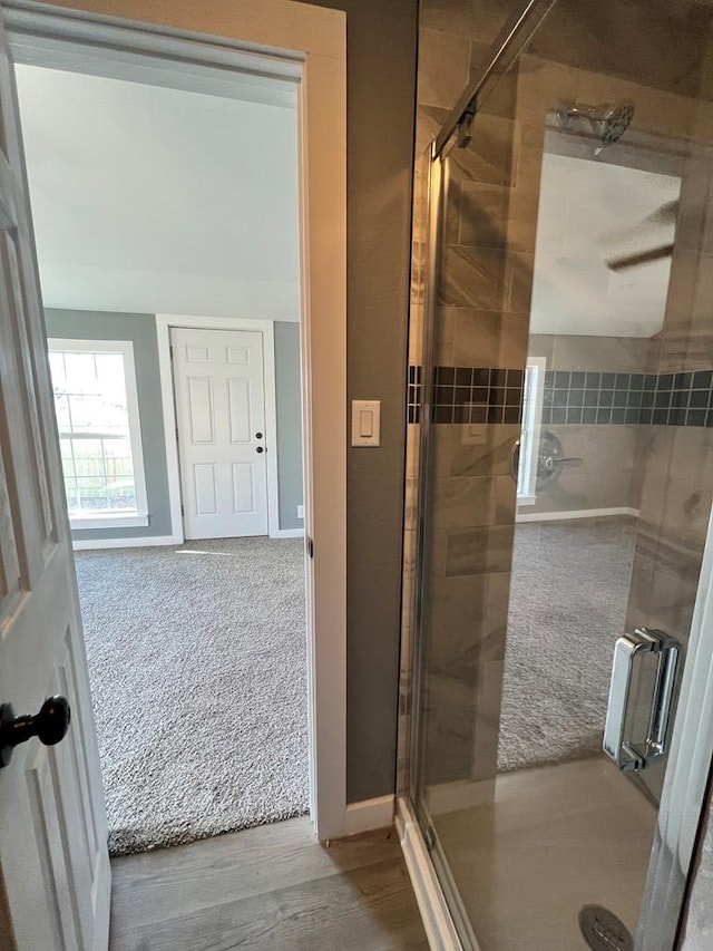 full bath with wood finished floors, baseboards, and a stall shower