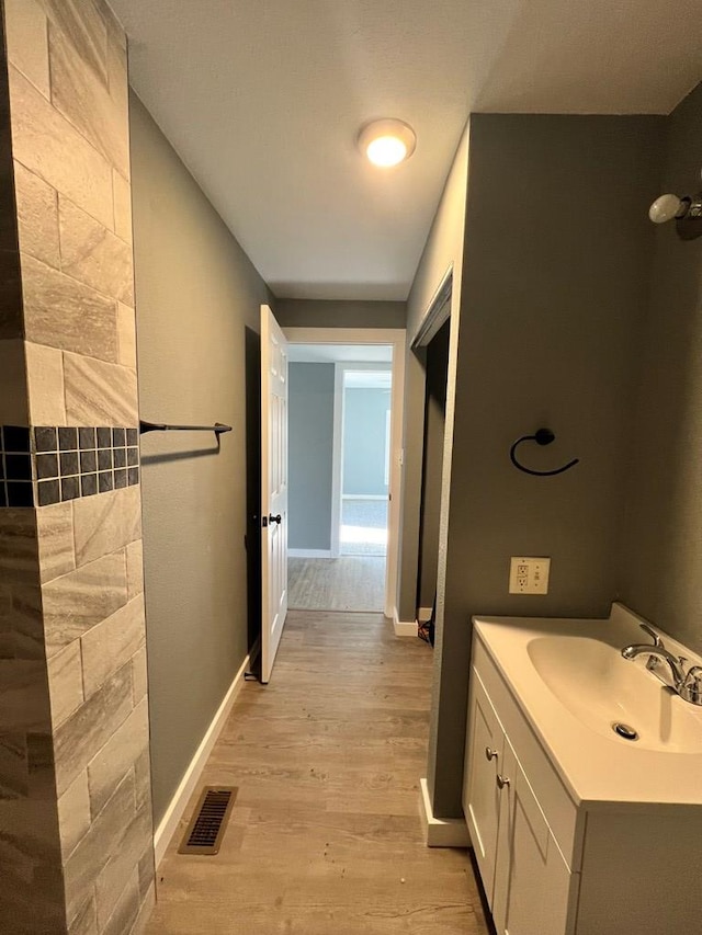 bathroom with vanity, wood finished floors, visible vents, and baseboards