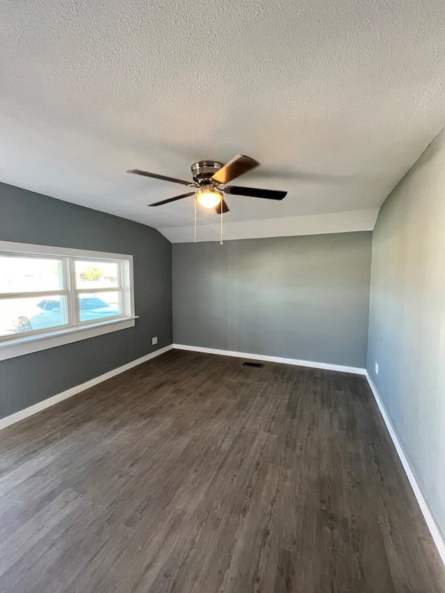 spare room featuring visible vents, a textured ceiling, dark wood finished floors, baseboards, and ceiling fan