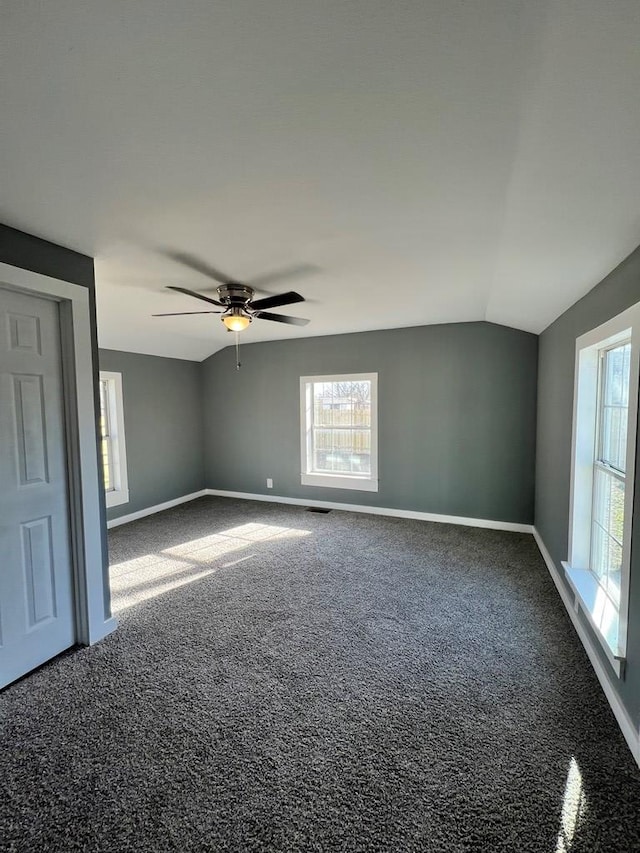 carpeted empty room featuring visible vents, ceiling fan, baseboards, and lofted ceiling