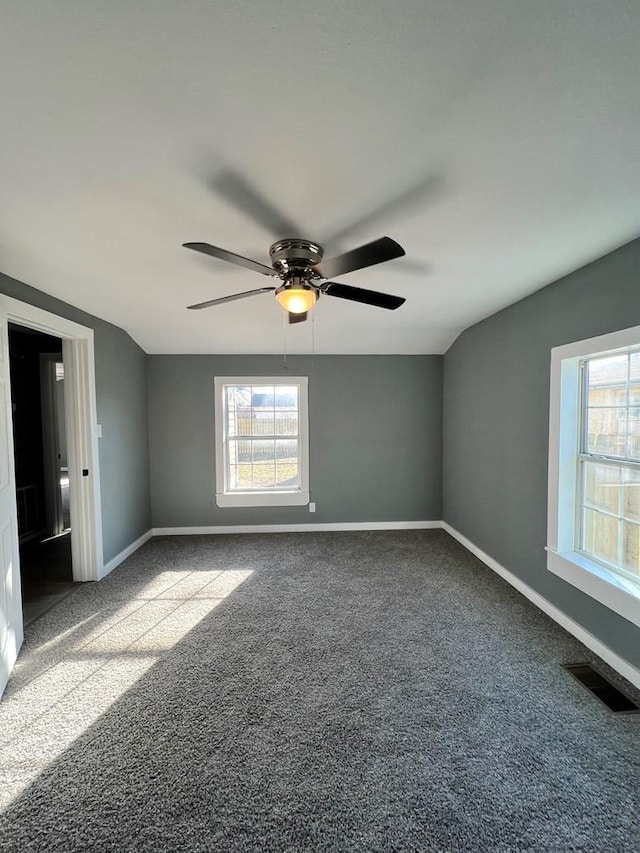 spare room with visible vents, baseboards, carpet flooring, and vaulted ceiling