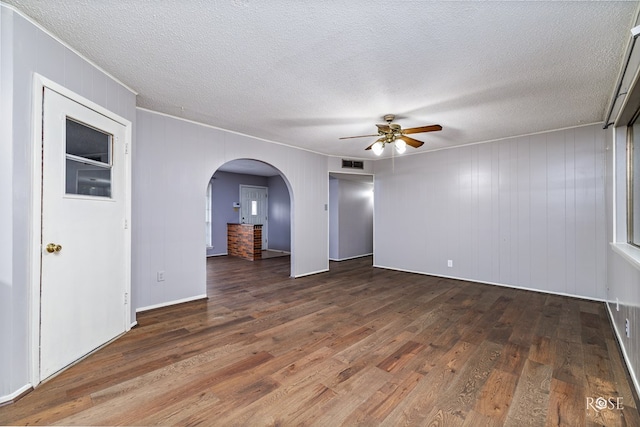 spare room featuring ceiling fan, dark hardwood / wood-style floors, and wooden walls