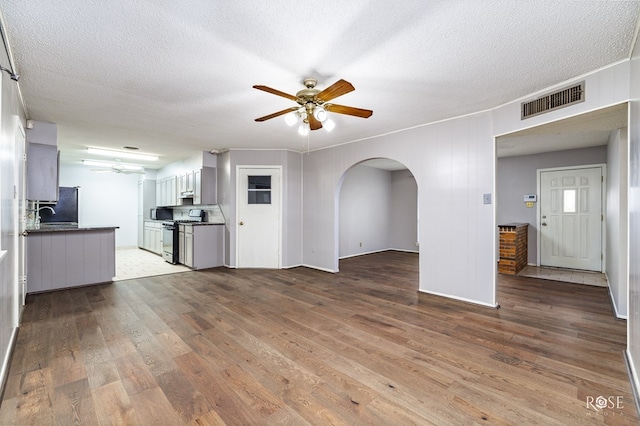 unfurnished living room with a textured ceiling, ceiling fan, and light hardwood / wood-style flooring