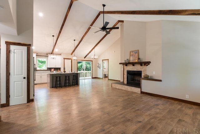 unfurnished living room featuring ceiling fan, high vaulted ceiling, beam ceiling, and hardwood / wood-style flooring