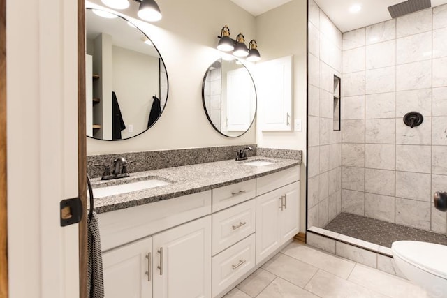 bathroom featuring dual bowl vanity, tile flooring, tiled shower, and toilet