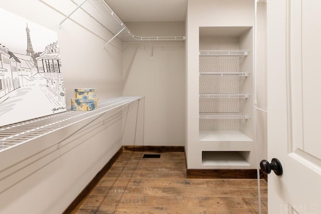 spacious closet with dark hardwood / wood-style flooring