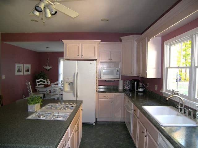 kitchen with appliances with stainless steel finishes, dark tile floors, white cabinets, ceiling fan, and sink