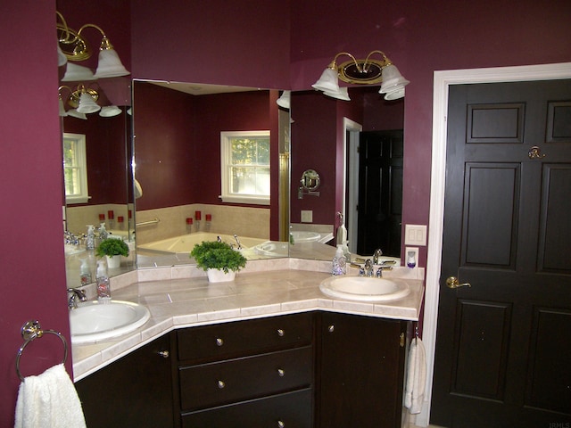 bathroom featuring double sink, a bath to relax in, plenty of natural light, and oversized vanity