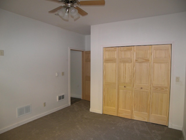 unfurnished bedroom featuring ceiling fan, a closet, and dark carpet