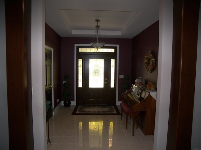 entryway with a raised ceiling and light tile floors