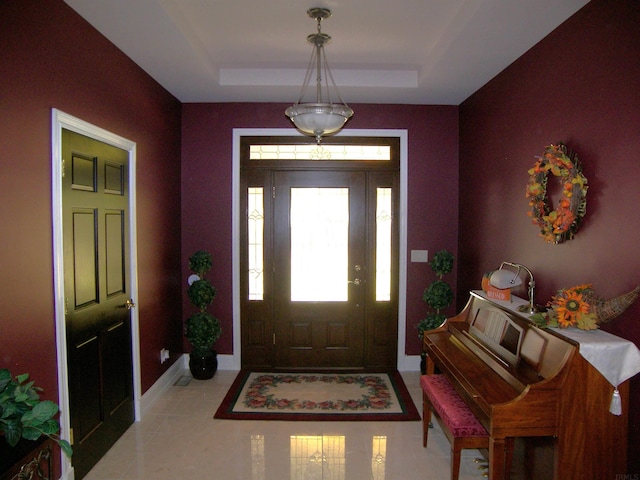 foyer with light tile flooring and a raised ceiling