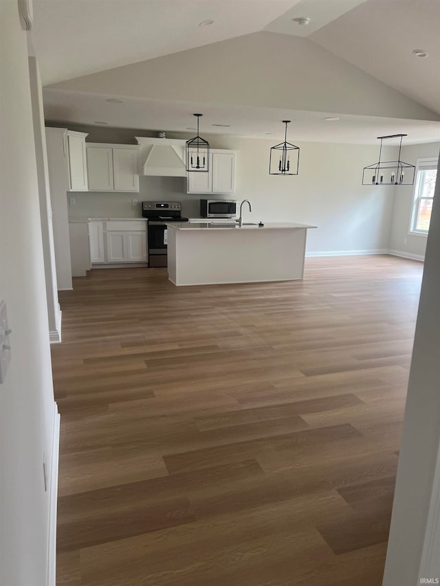 kitchen featuring white cabinets, hanging light fixtures, hardwood / wood-style floors, appliances with stainless steel finishes, and an island with sink