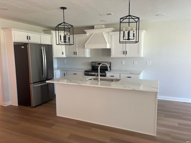 kitchen with white cabinets, appliances with stainless steel finishes, an island with sink, and custom range hood