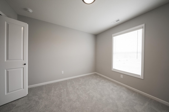 carpeted spare room with visible vents and baseboards