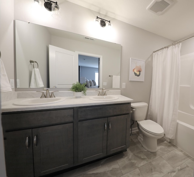 bathroom with toilet, double vanity, a sink, and visible vents