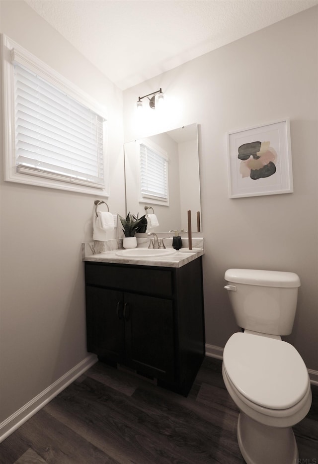 bathroom featuring toilet, vanity, baseboards, and wood finished floors