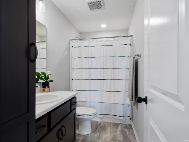 full bathroom with toilet, visible vents, and vanity