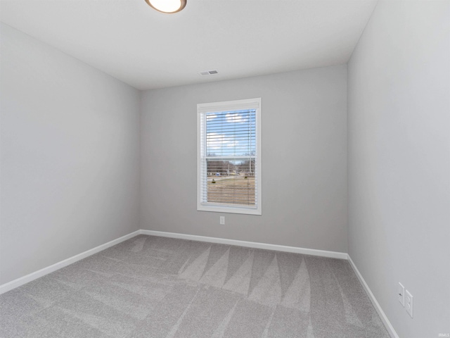 empty room with carpet floors, visible vents, and baseboards