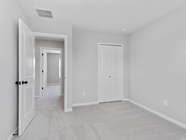 unfurnished bedroom featuring light carpet, a closet, visible vents, and baseboards