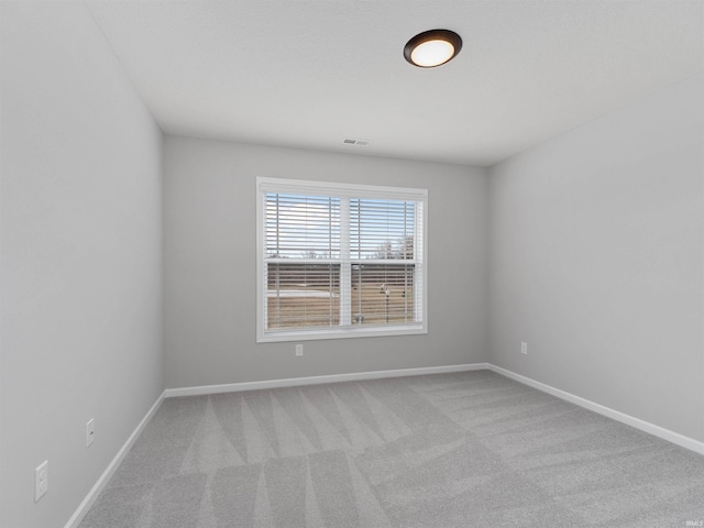 empty room with light carpet, visible vents, and baseboards