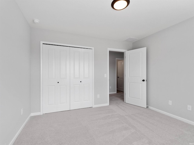 unfurnished bedroom featuring a closet, light colored carpet, and baseboards