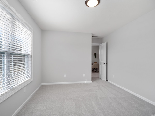 unfurnished room with light carpet, visible vents, and baseboards