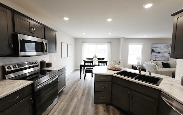 kitchen with decorative backsplash, stainless steel appliances, a sink, and light countertops