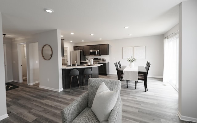 living room featuring light wood-type flooring, baseboards, and recessed lighting