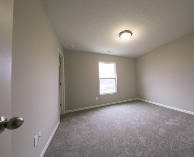 carpeted empty room featuring a textured ceiling