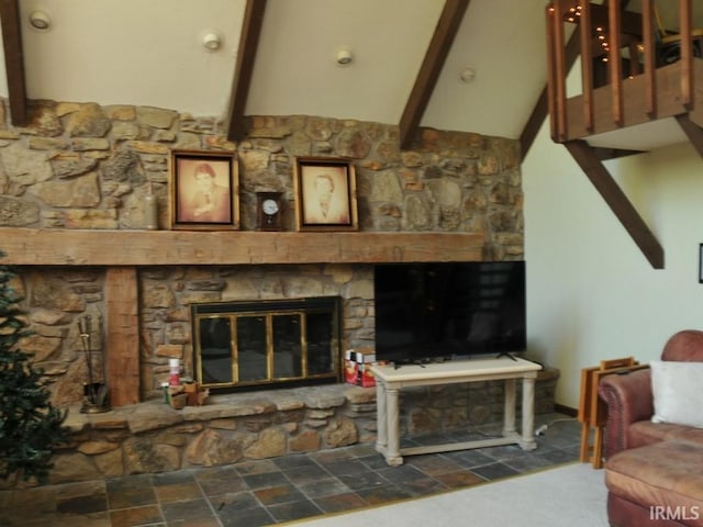 living room featuring beamed ceiling and a stone fireplace