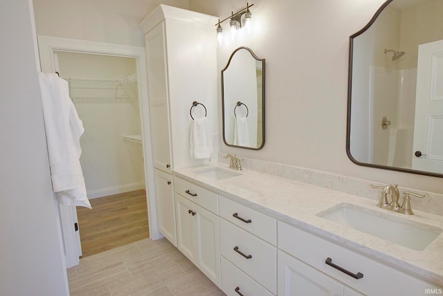 bathroom with tile flooring, a shower, and double vanity