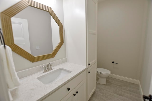 bathroom with toilet and vanity with extensive cabinet space
