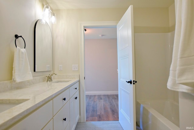 bathroom featuring hardwood / wood-style floors, dual vanity, and washtub / shower combination