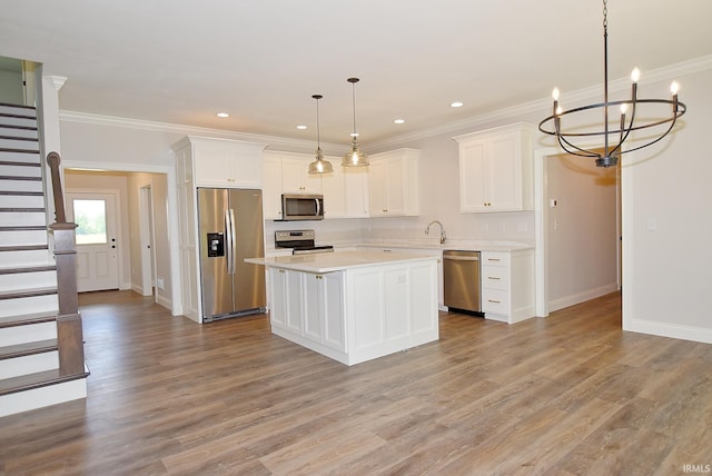 kitchen featuring hanging light fixtures, stainless steel appliances, light hardwood / wood-style floors, white cabinetry, and a chandelier