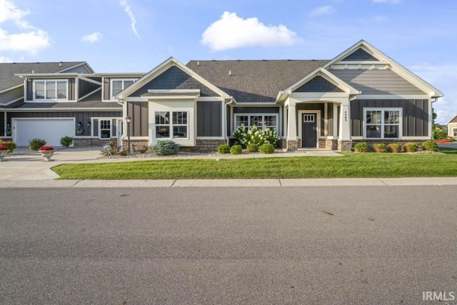 craftsman inspired home featuring a garage and a front lawn