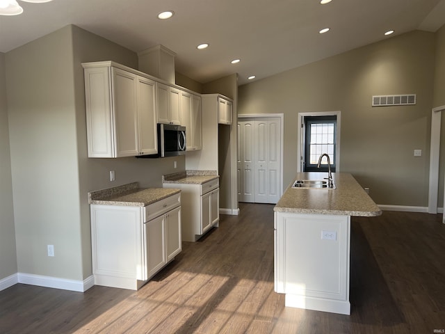 kitchen featuring vaulted ceiling, dark hardwood / wood-style flooring, a kitchen island with sink, and sink