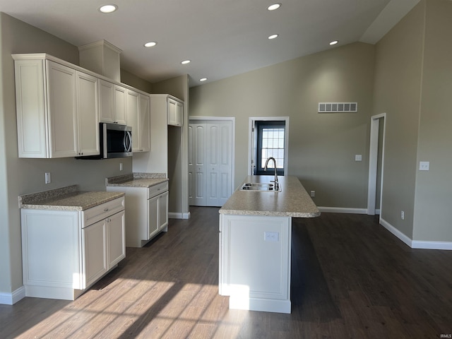 kitchen featuring sink, dark hardwood / wood-style floors, an island with sink, and white cabinets