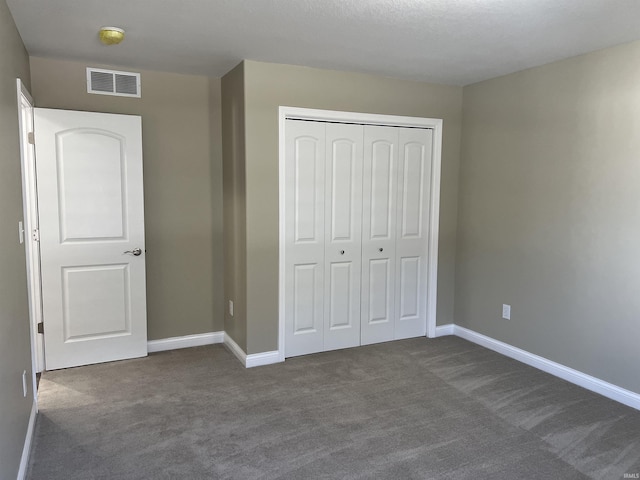 unfurnished bedroom with a closet and dark colored carpet