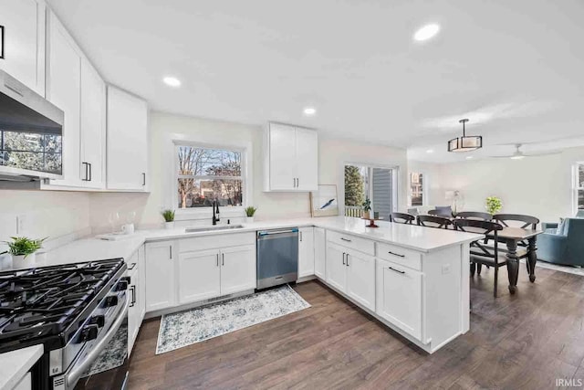 1114 Beacon Dr, Mishawaka, IN 46544 - kitchen with dark wood finished floors, a peninsula, light countertops, a sink, and stainless steel appliances
