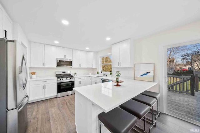 1114 Beacon Dr, Mishawaka, IN 46544 - kitchen featuring light countertops, appliances with stainless steel finishes, a breakfast bar, light wood-style floors, and a peninsula
