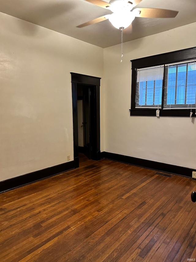 unfurnished room with ceiling fan and dark wood-type flooring