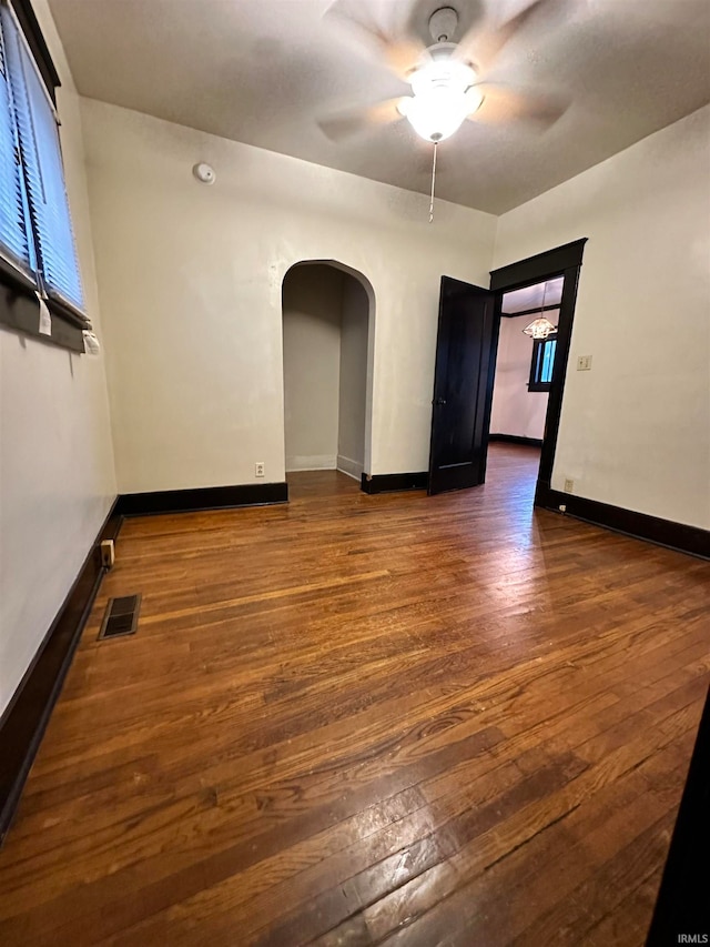 empty room with ceiling fan and dark wood-type flooring