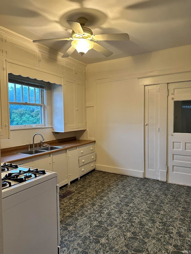 kitchen with white cabinetry, gas range gas stove, dark tile floors, and ceiling fan