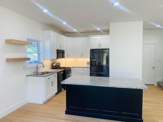 kitchen with white cabinets, a center island, sink, and black appliances