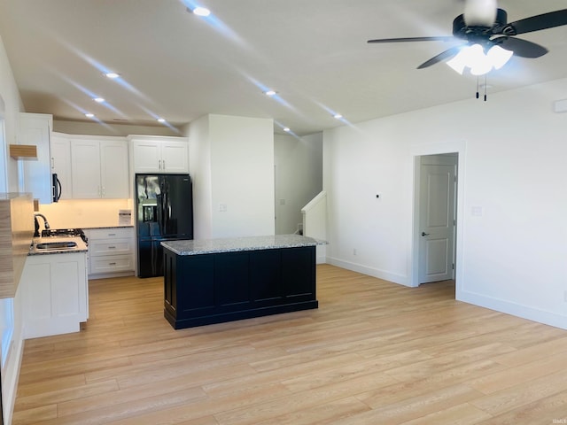 kitchen featuring sink, white cabinetry, a kitchen island, and black appliances